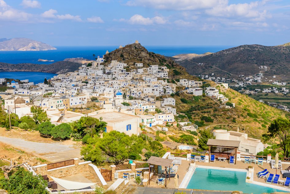 A stunning photo of Ios in greece from aerial view, with the mountains, lush greenery and deep blue sea in view 