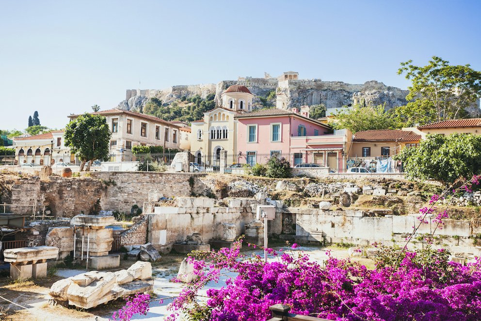 A view of houses in Athens, Greece, with bright purple flowers in view.